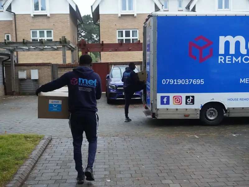 Two MET Removals movers carrying branded boxes to a single removals van, man and van moves in Walthamstow