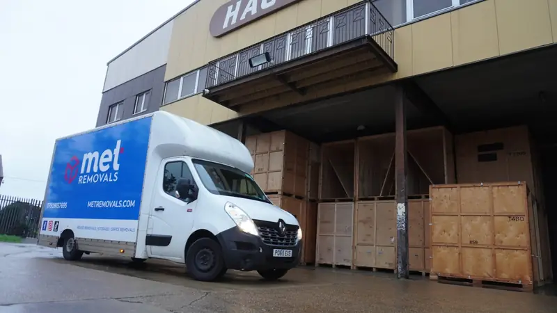 MET Removals van outside a warehouse stacked with wooden storage containers, storage for Crouch End customers