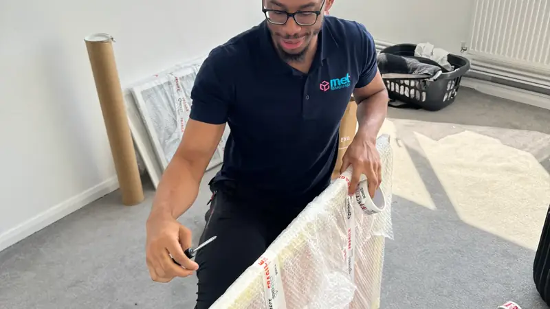 MET Removals mover wrapping a framed picture in bubble wrap and fragile tape, careful handling for office removals in Buckhurst Hill