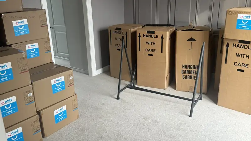 Stacked MET Removals boxes and wardrobe cartons in a bedroom, packing services in Buckhurst Hill