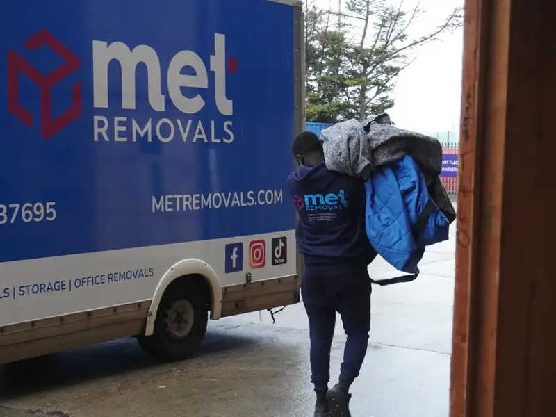 MET Removals mover carrying protective blankets to a branded removals van, office removals in Walthamstow