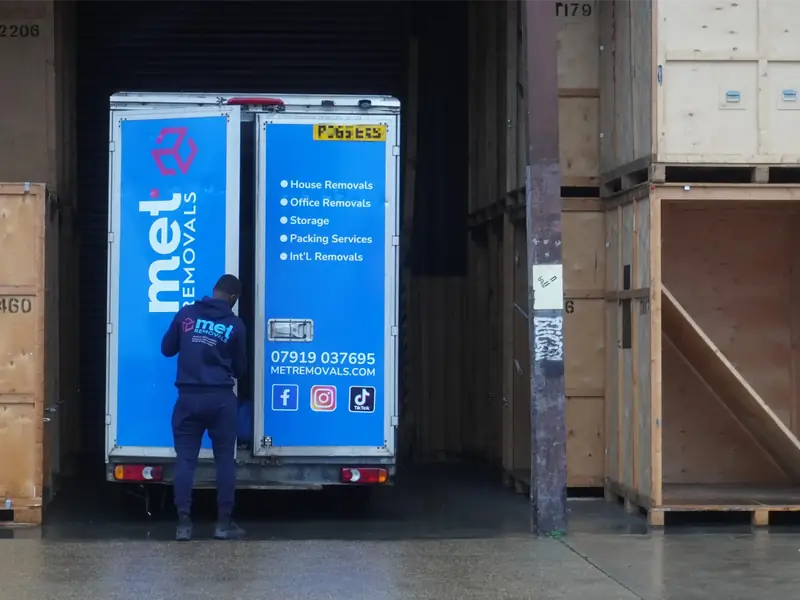 MET Removals team member at the back of a MET Removals van beside wooden storage containers, secure storage for Buckhurst Hill moves